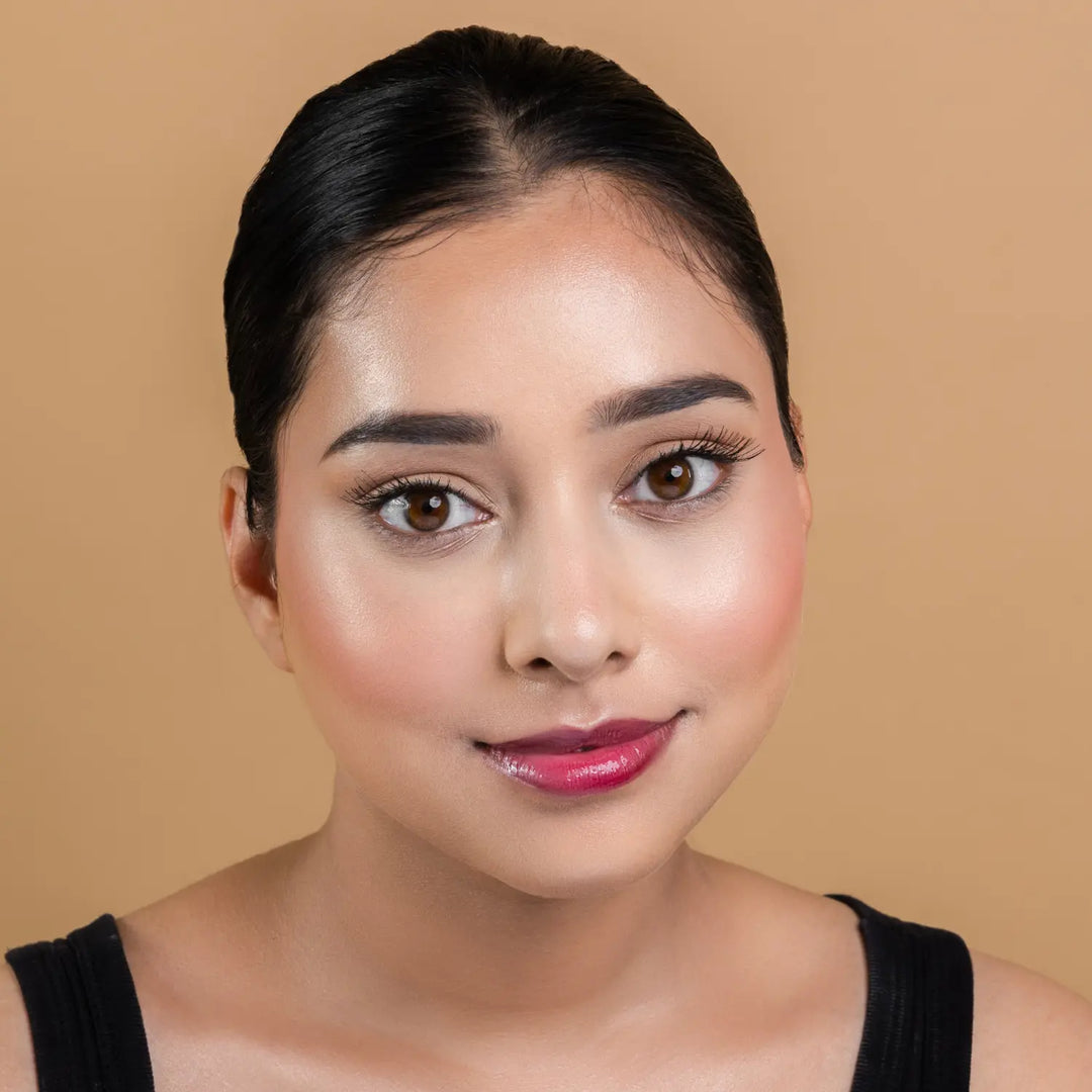 MyHues HyGlow Lip Elixir in Noor – deep burgundy lip gloss shown on fair Indian skin tone, high shine hydrating lip gloss with rich pigmentation and smooth non sticky glossy finish